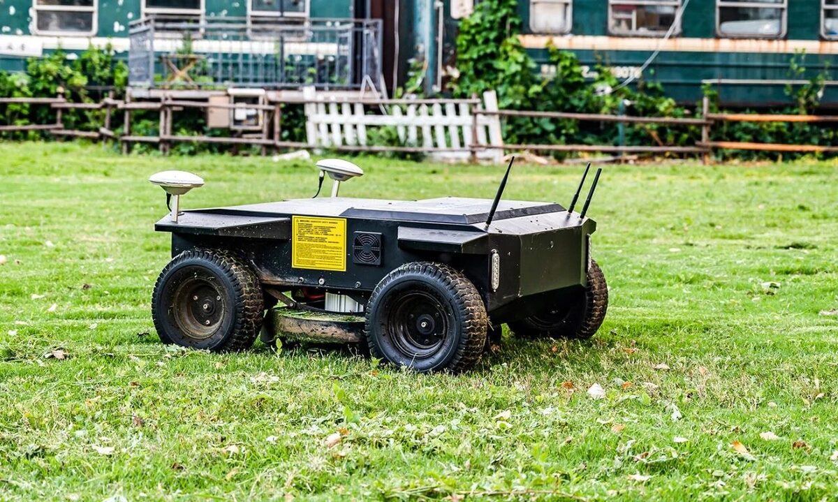 All-electric WANJI R1 autonomous mower on the lawn of a train-themed glamping site