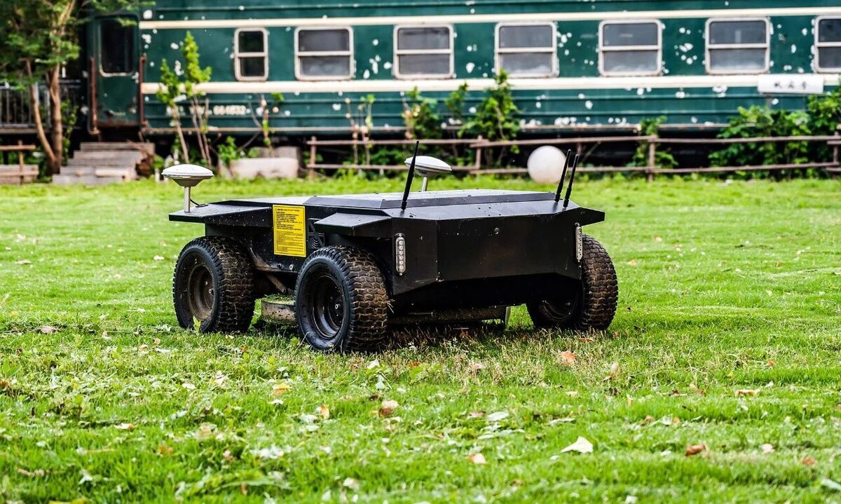 Quiet autonomous mower on campground lawn with themed carriages behind