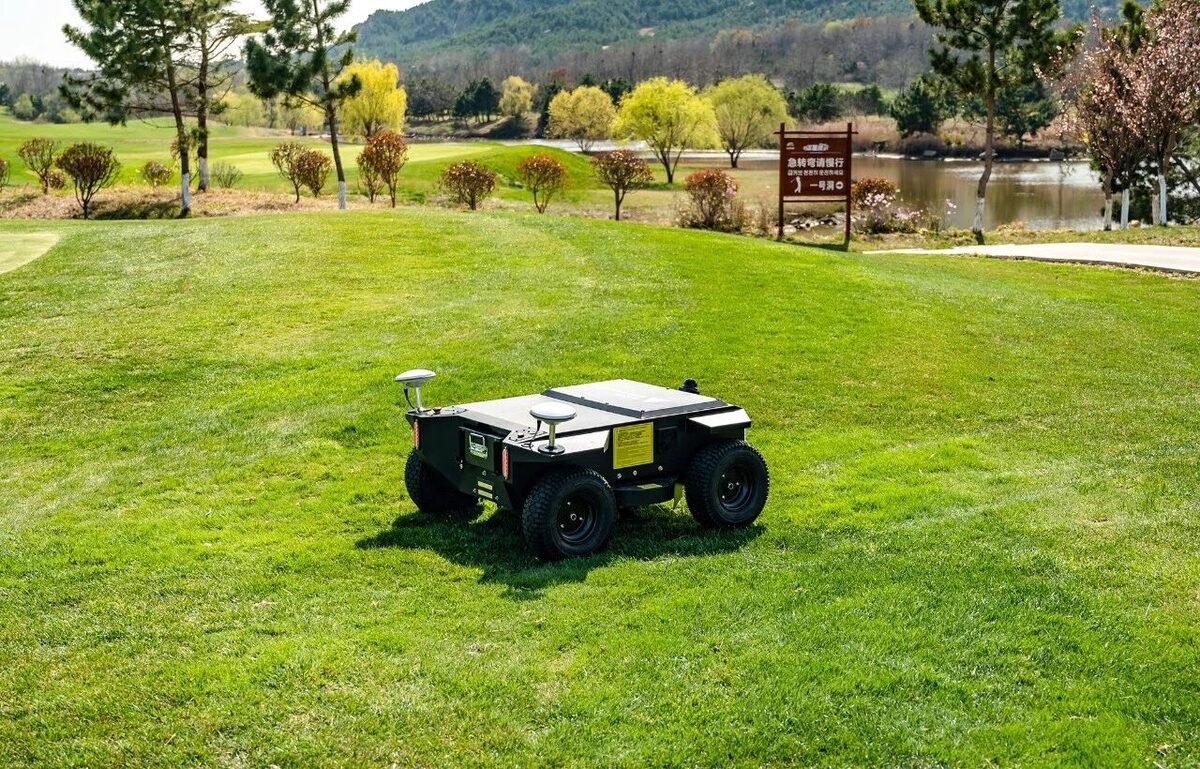Wheeled autonomous mower on a golf course beside a water hazard