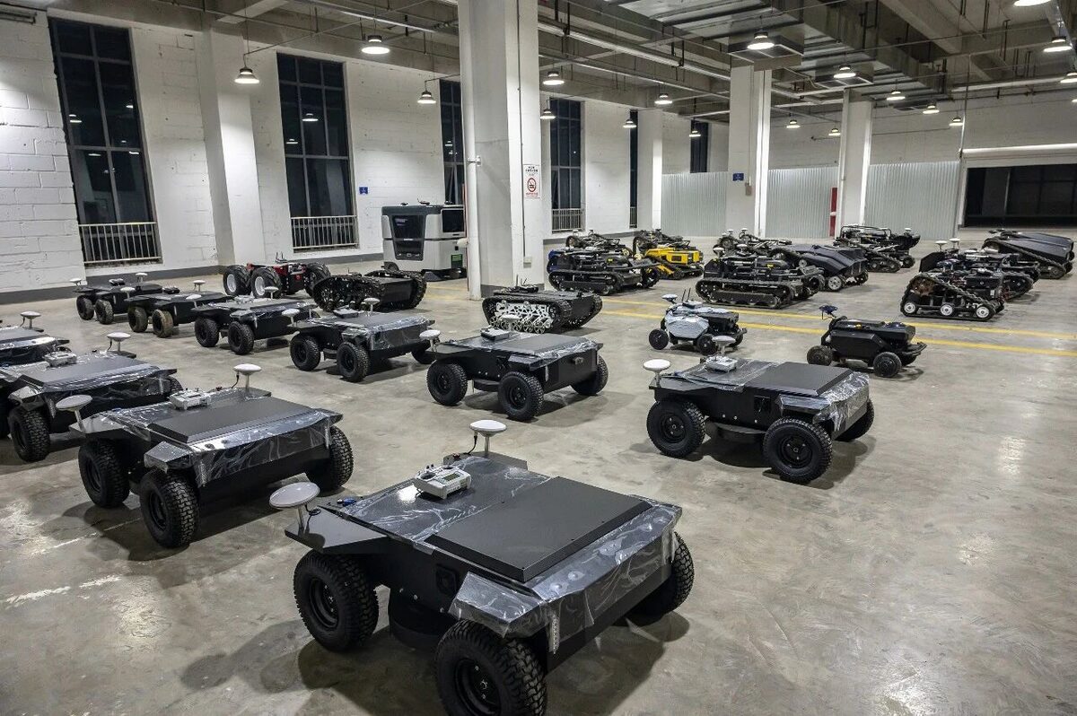 Rows of wheeled and tracked autonomous mowers on the production floor